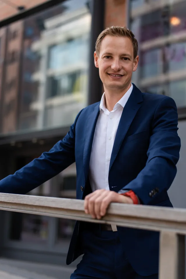 Businessportrait eines Mannes im blauen Anzug auf einer Brücke in der Hamburger HafenCity